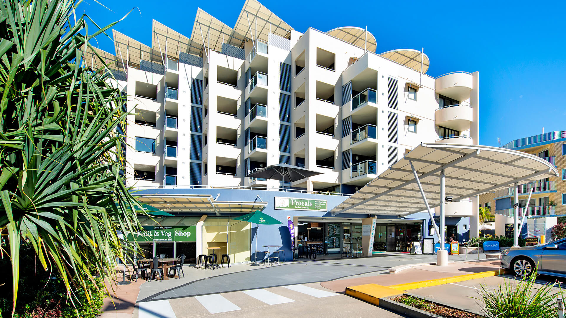 Exterior view of ULTIQA Shearwater Resort with balconies and ground-floor shops.