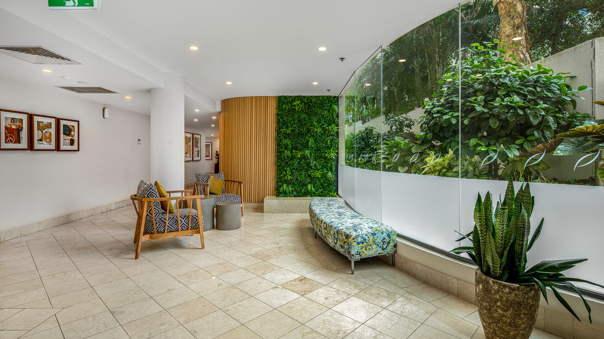 Lobby seating area at ULTIQA Shearwater Resort featuring indoor greenery, modern chairs and large windows overlooking lush garden views.