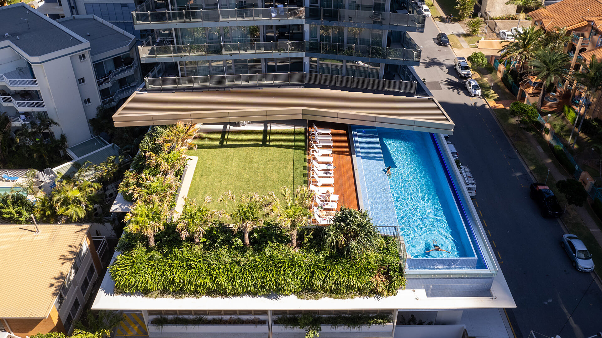 Aerial view of ULTIQA Signature's rooftop pool, sun loungers and landscaped garden area.