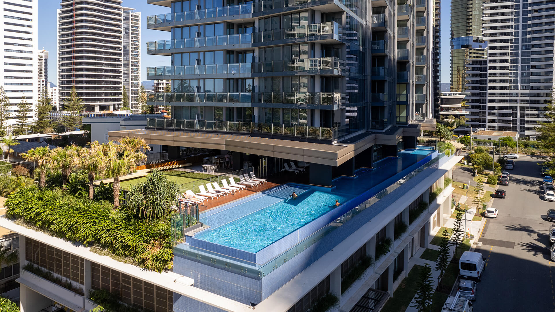 Infinity pool and sun deck at ULTIQA Signature surrounded by lush greenery and modern high-rises.