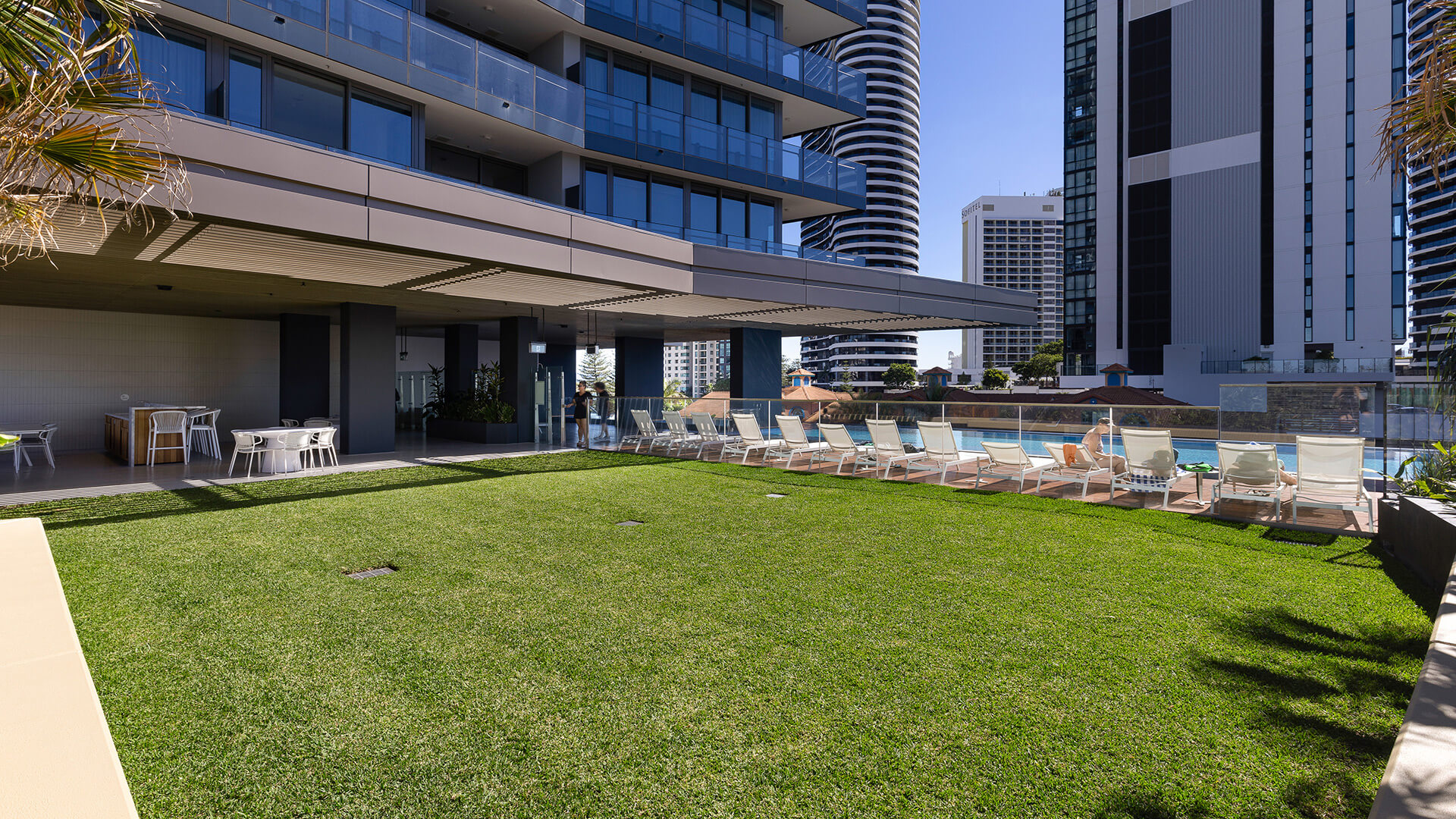 Spacious outdoor lawn area at ULTIQA Signature with sun loungers and city views.