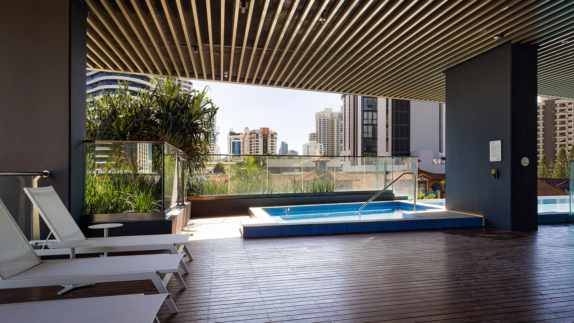Covered spa area at ULTIQA Signature with sun loungers and city skyline views.