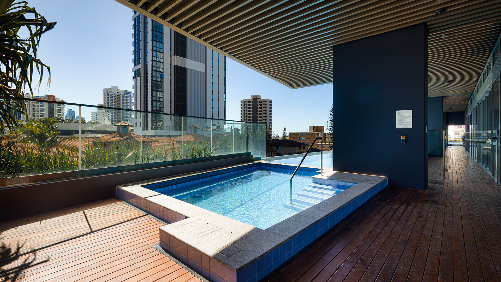 Outdoor spa at ULTIQA Signature with timber deck and city skyline views.