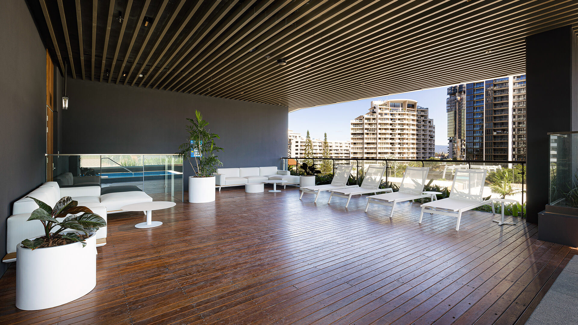 Shaded lounge area at ULTIQA Signature with white sunbeds, sofas and city views.