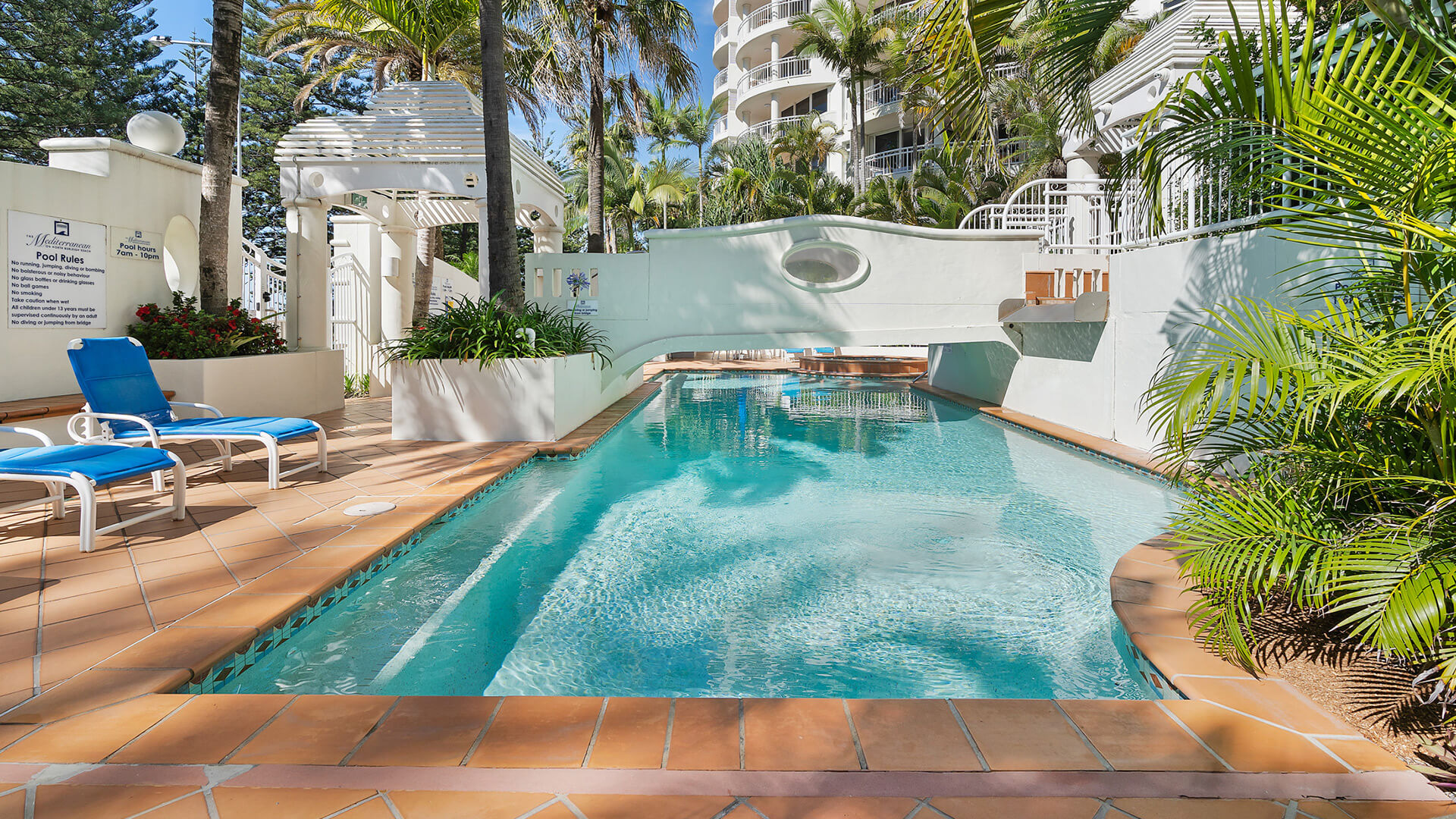 Outdoor pool area with sun loungers at ULTIQA Burleigh Mediterranean Resort.