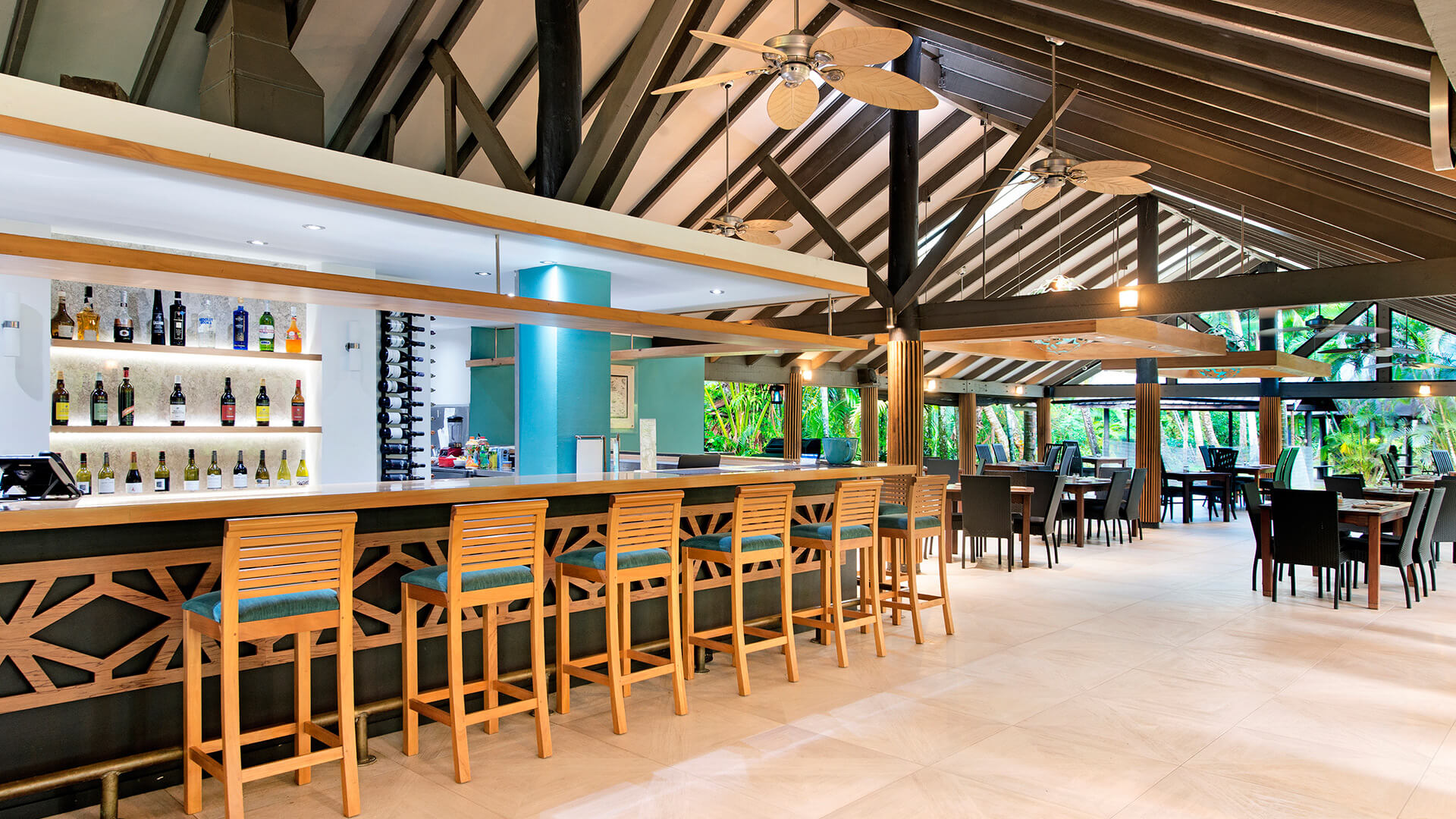 Stylish bar and dining area at ULTIQA Fiji with high stools, modern decor and open-air tropical setting.