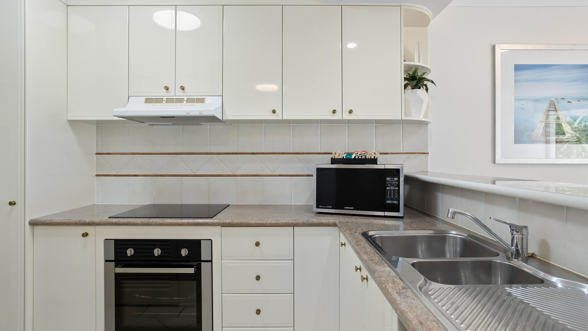 Full kitchen featuring oven, microwave, double sink, and ample storage.