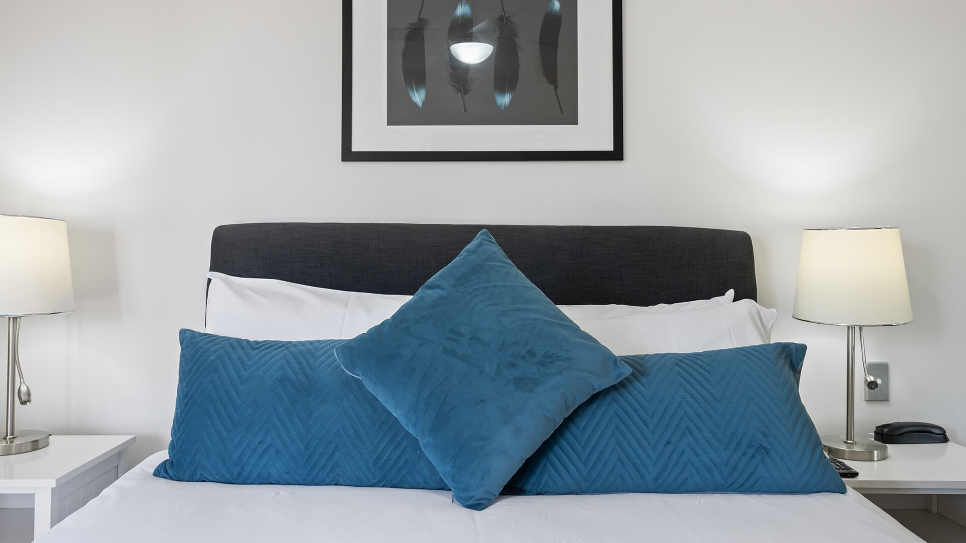 Close-up of the king bed styled with blue feature cushions and soft lighting.