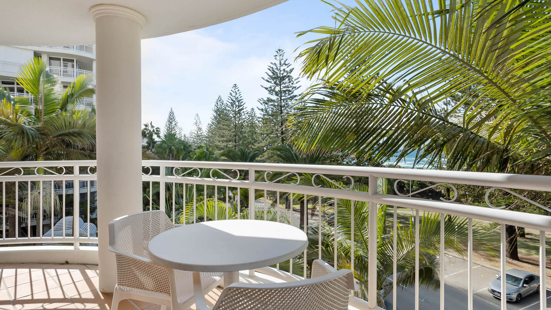 Private balcony offering partial ocean views and tropical surrounds.