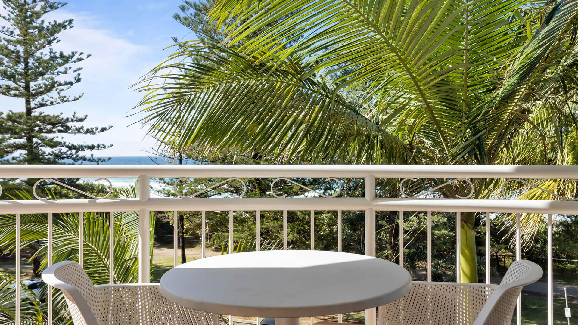 Outdoor dining area on the private balcony with views of the ocean and surrounding palms.