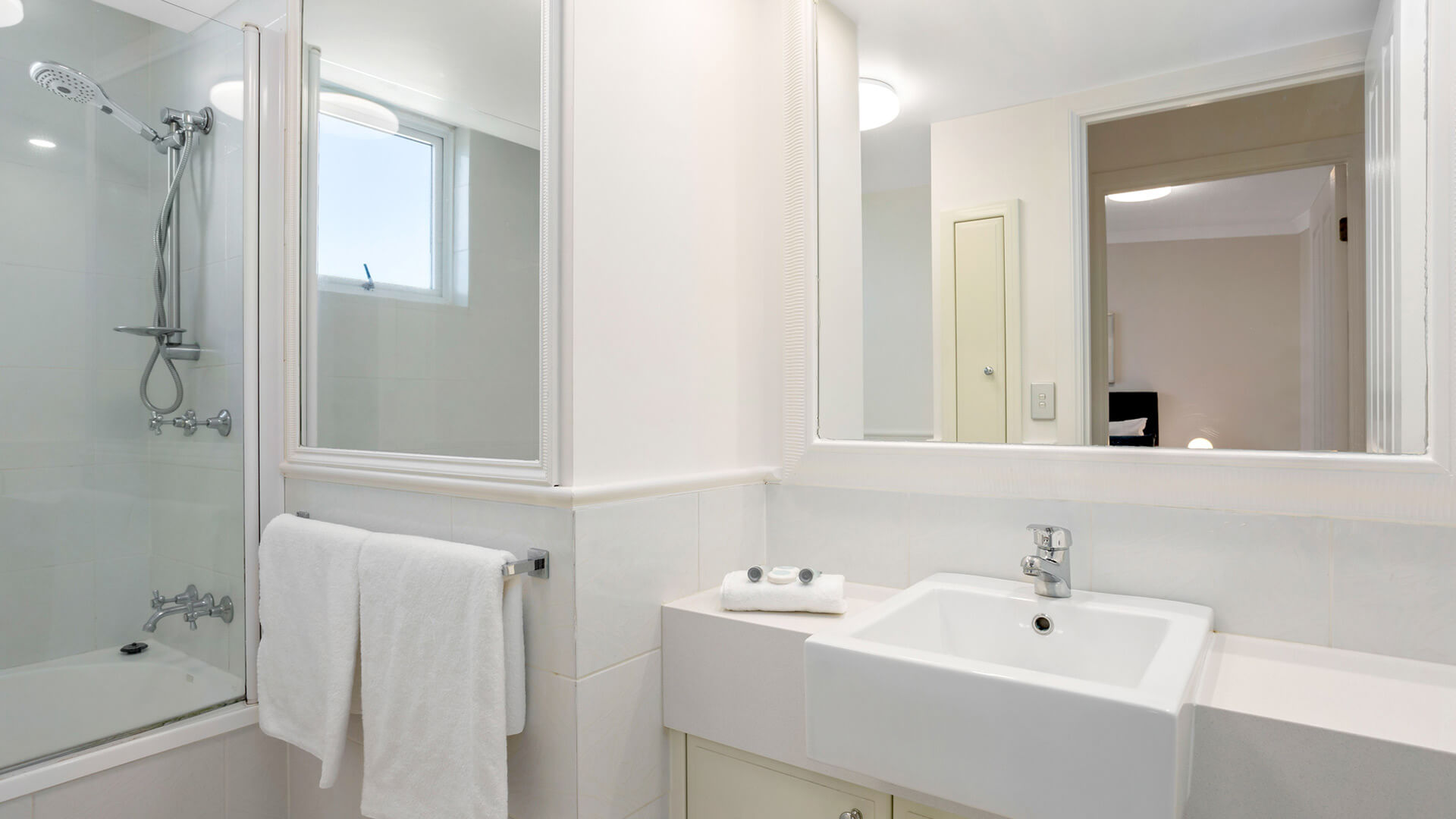 Modern bathroom in shower over bathtub and vanity.