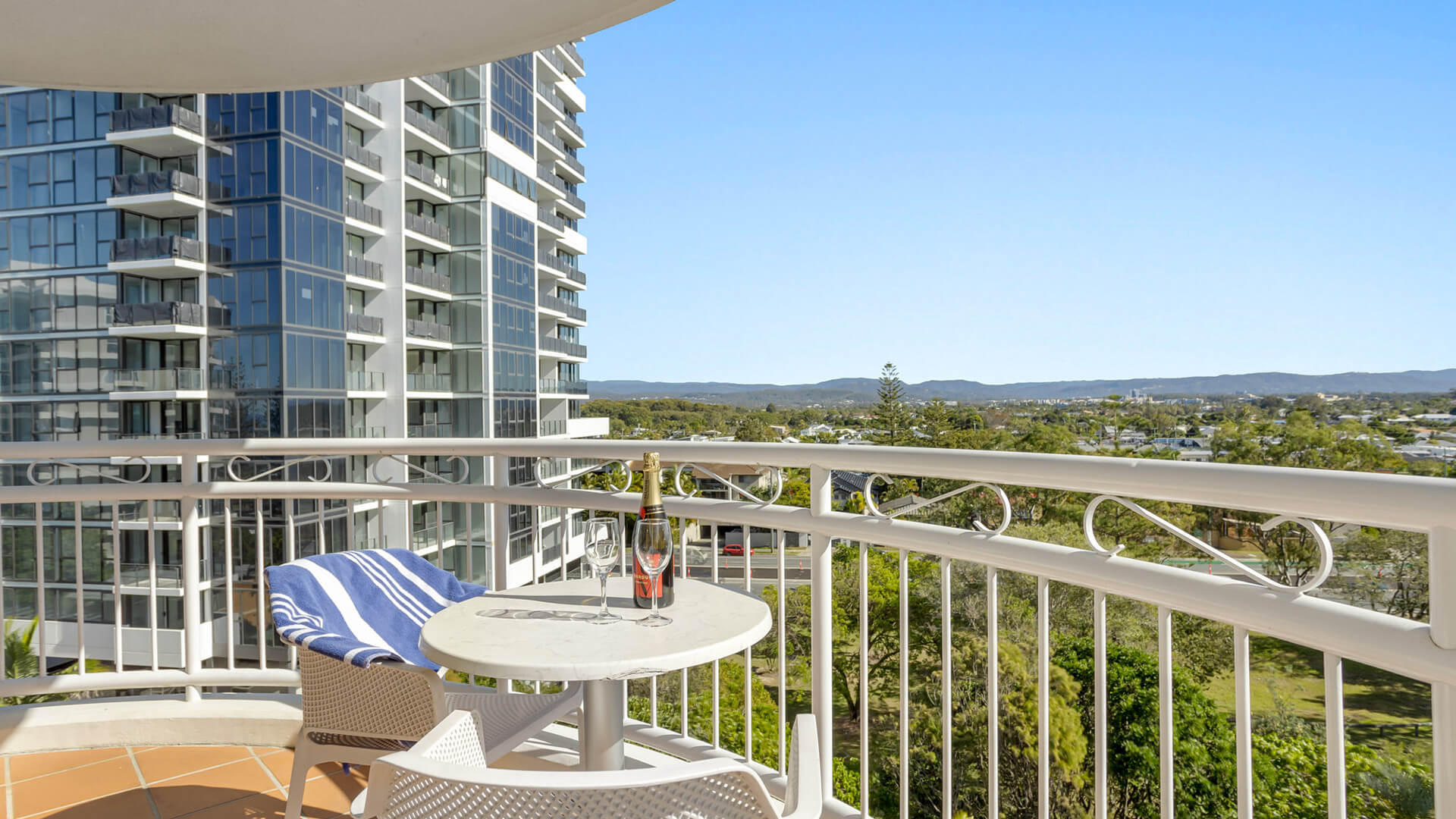 Private balcony with hinterland views, outdoor seating, and a bottle of sparkling wine.