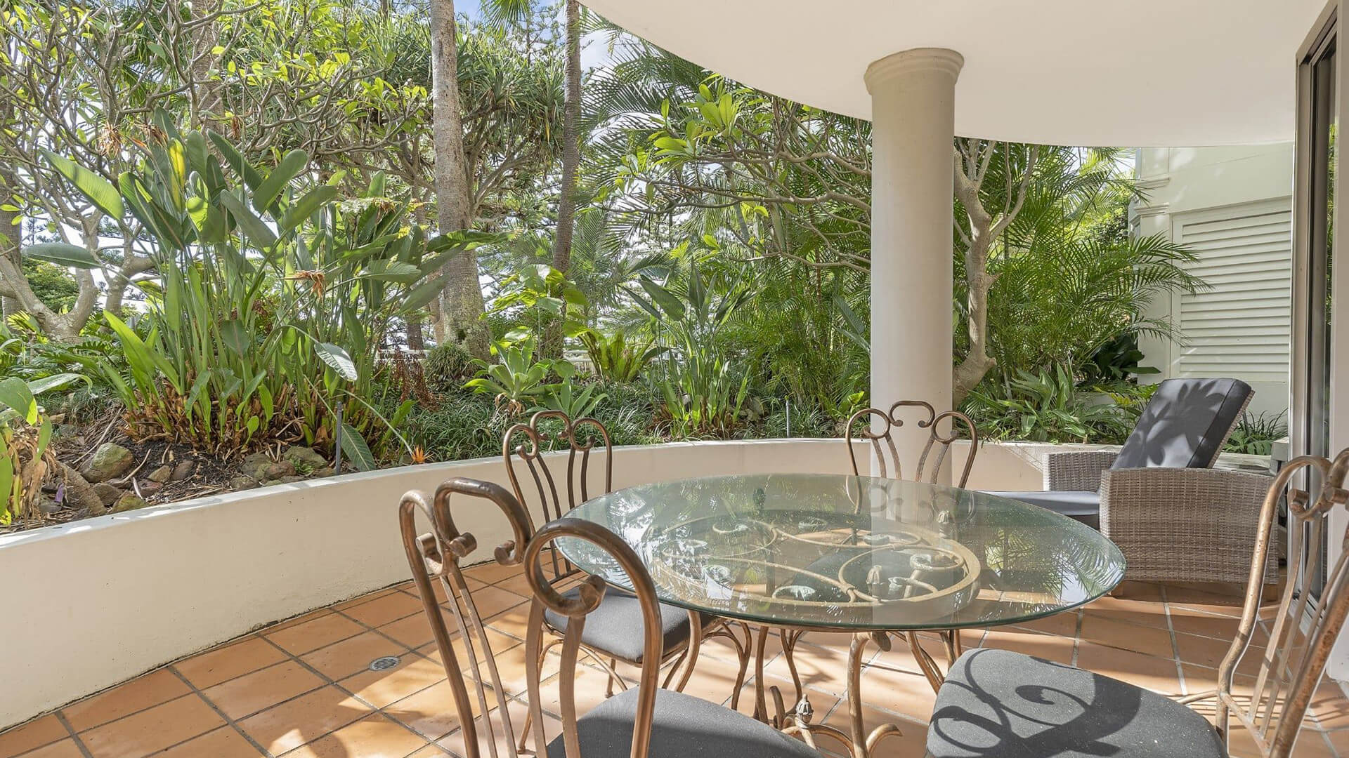 Private outdoor patio in 1 Bedroom Superior Apartment at ULTIQA Burleigh Mediterranean Resort with garden views and dining setting.
