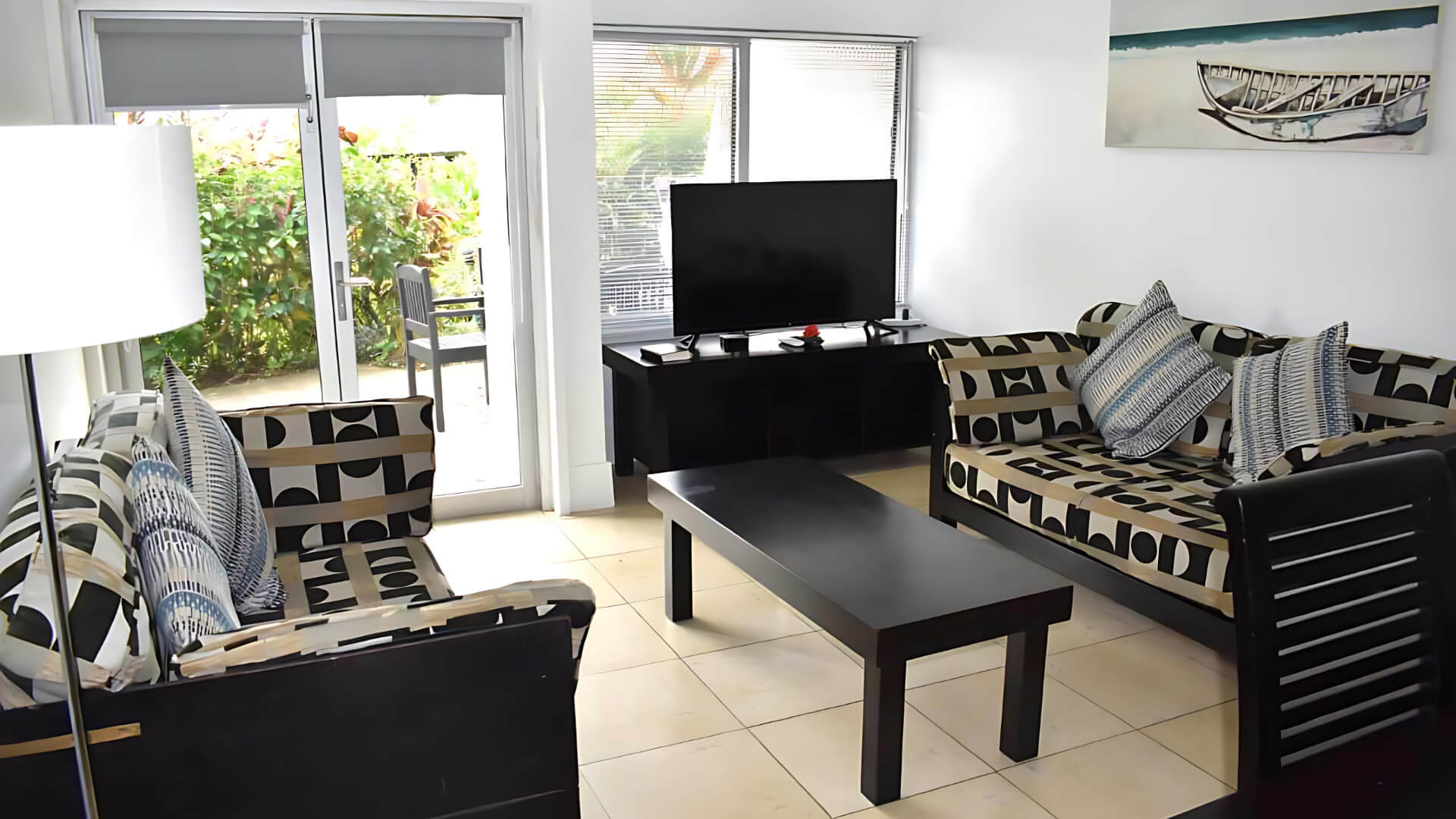 Living area of Standard 2 Bedroom 1 Bathroom Apartment at ULTIQA Fiji, with sofas, TV, and patio access.