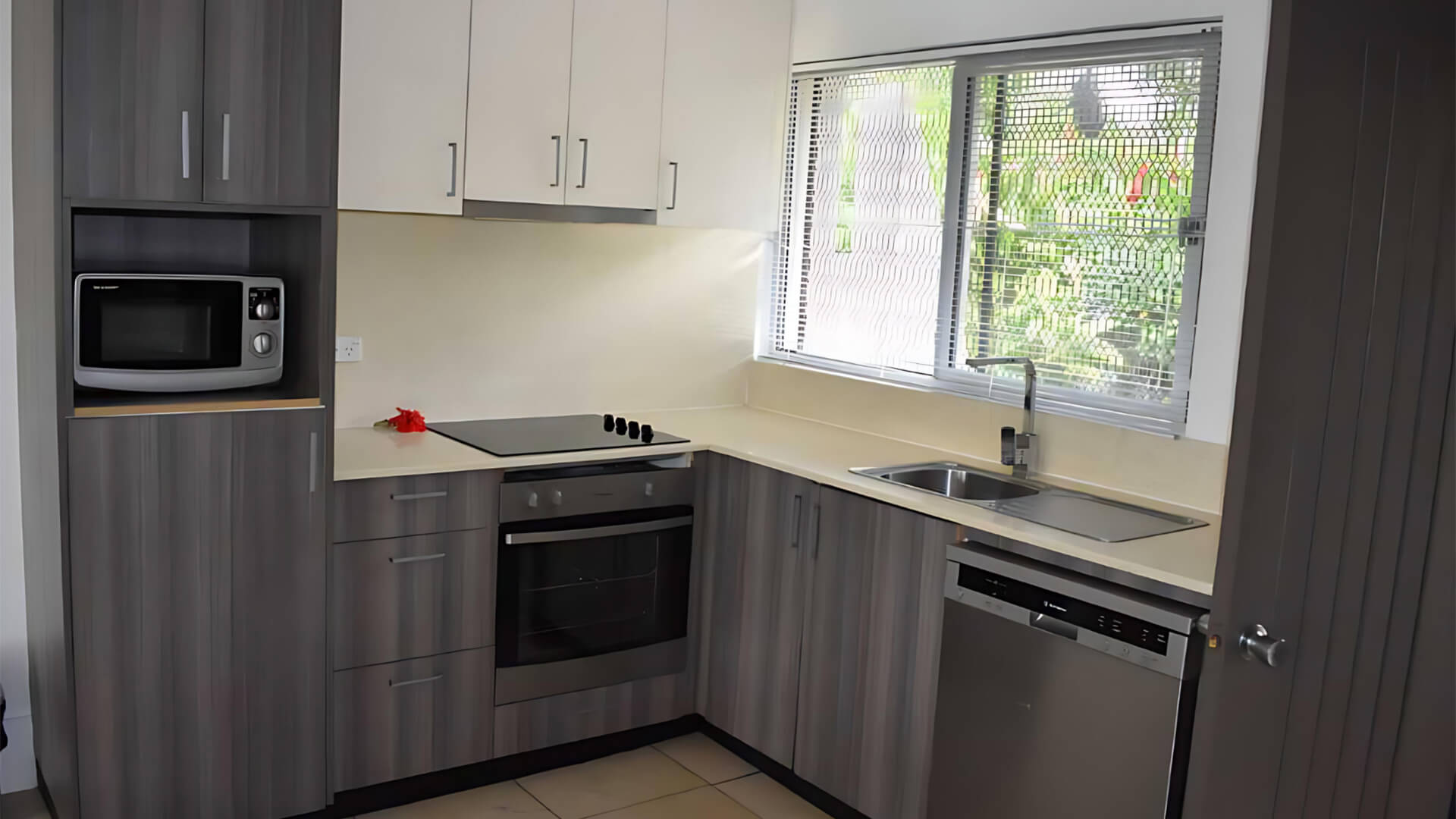 Fully equipped kitchen in Standard 2 Bedroom 1 Bathroom Apartment at ULTIQA Fiji, featuring oven, cooktop, microwave, dishwasher, and ample storage.
