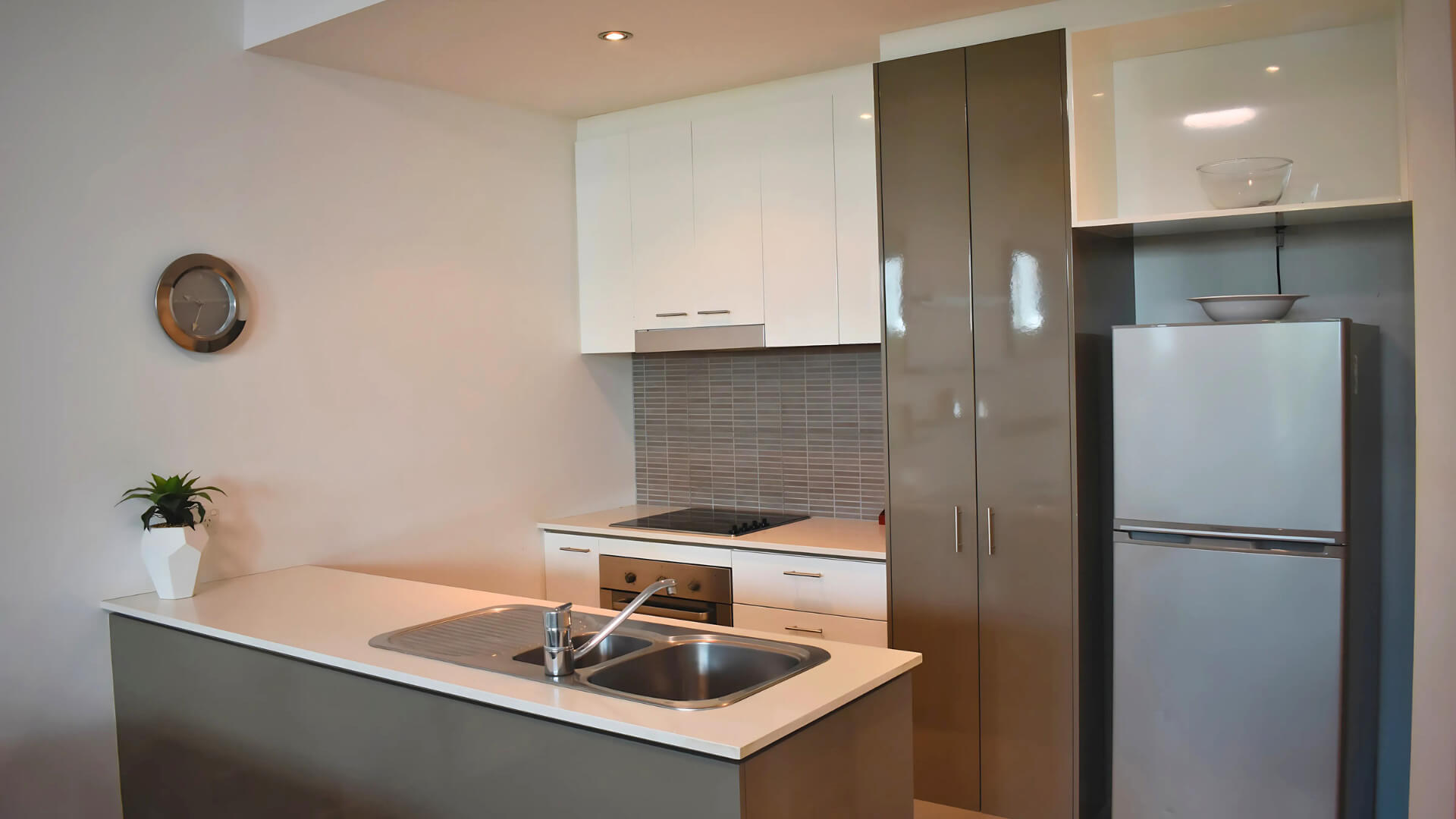 Compact kitchenette in the studio at ULTIQA Freshwater Point Resort with fridge, cooktop, and sink.