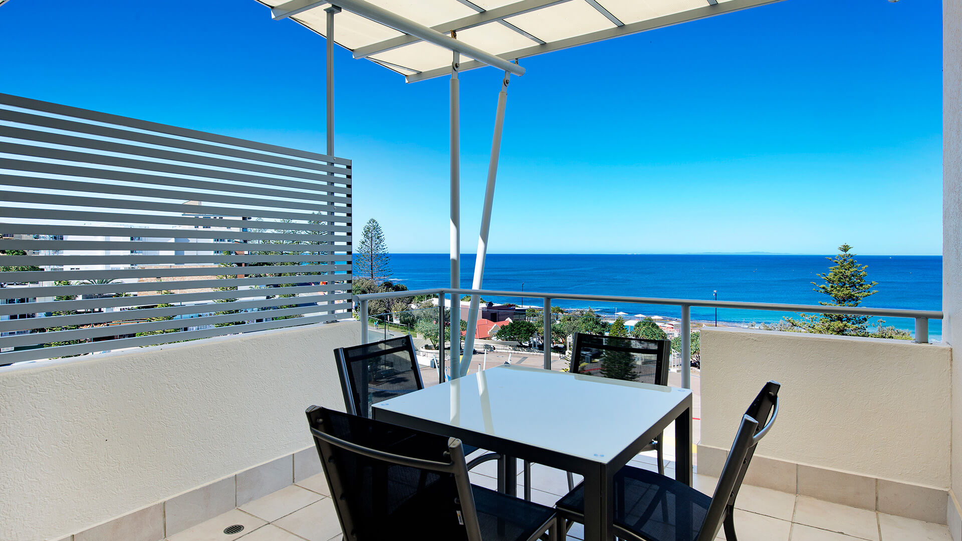 Private balcony with outdoor dining and ocean views in 1-Bedroom Apartment at ULTIQA Shearwater Resort.