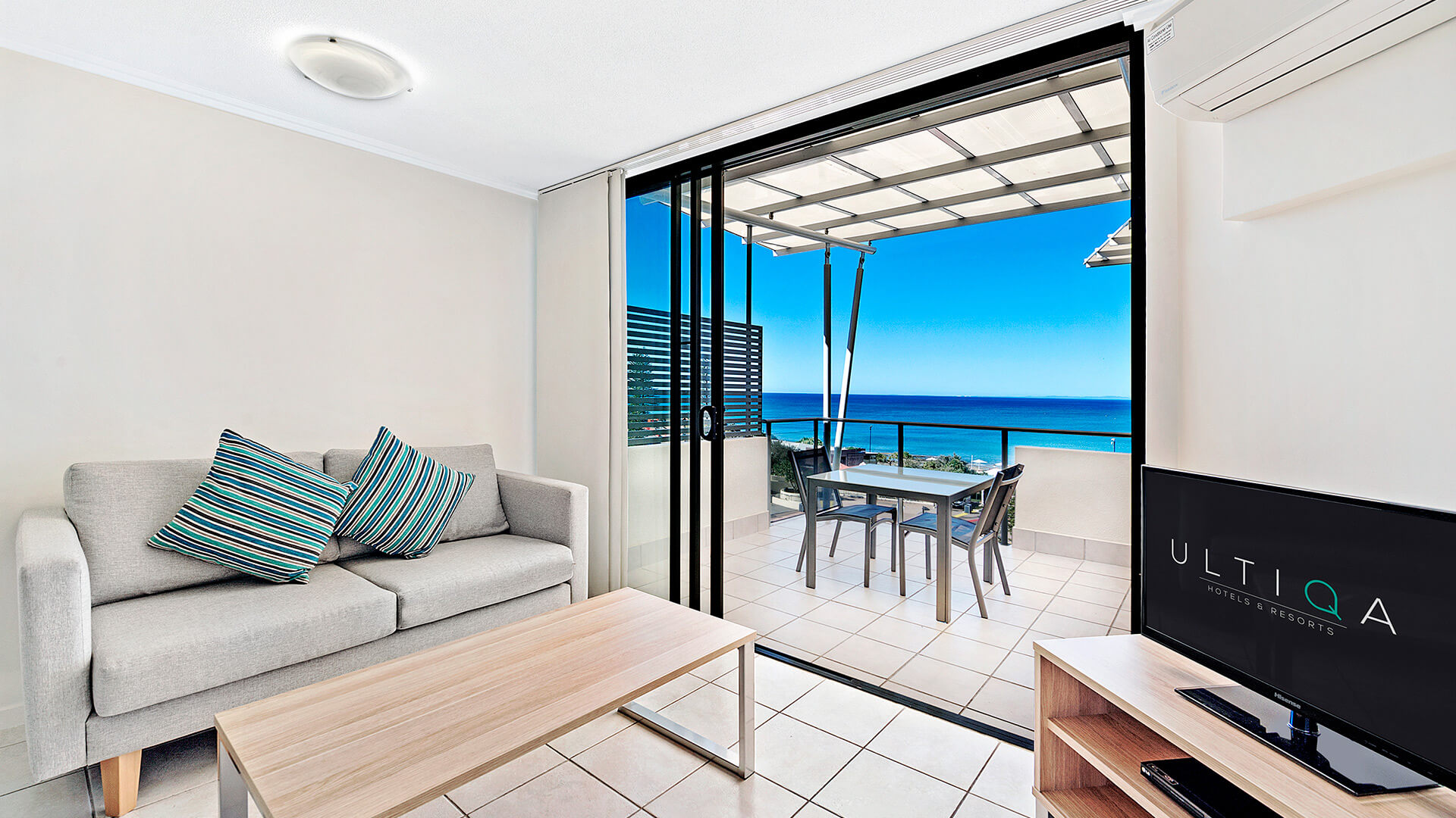 Living area with ocean views and balcony access in 1 Bedroom Apartment at ULTIQA Shearwater Resort.
