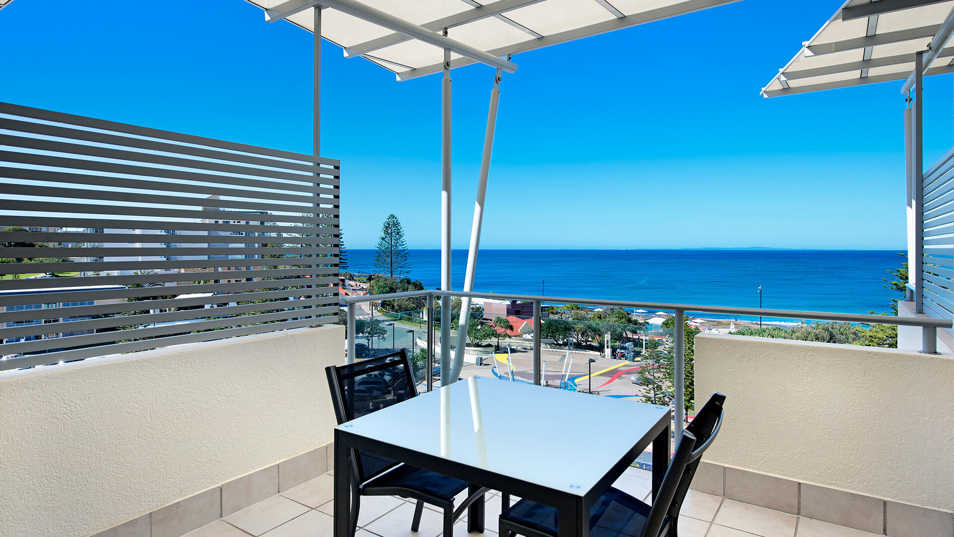 Private balcony with outdoor dining and ocean views from 1 Bedroom Apartment at ULTIQA Shearwater Resort.