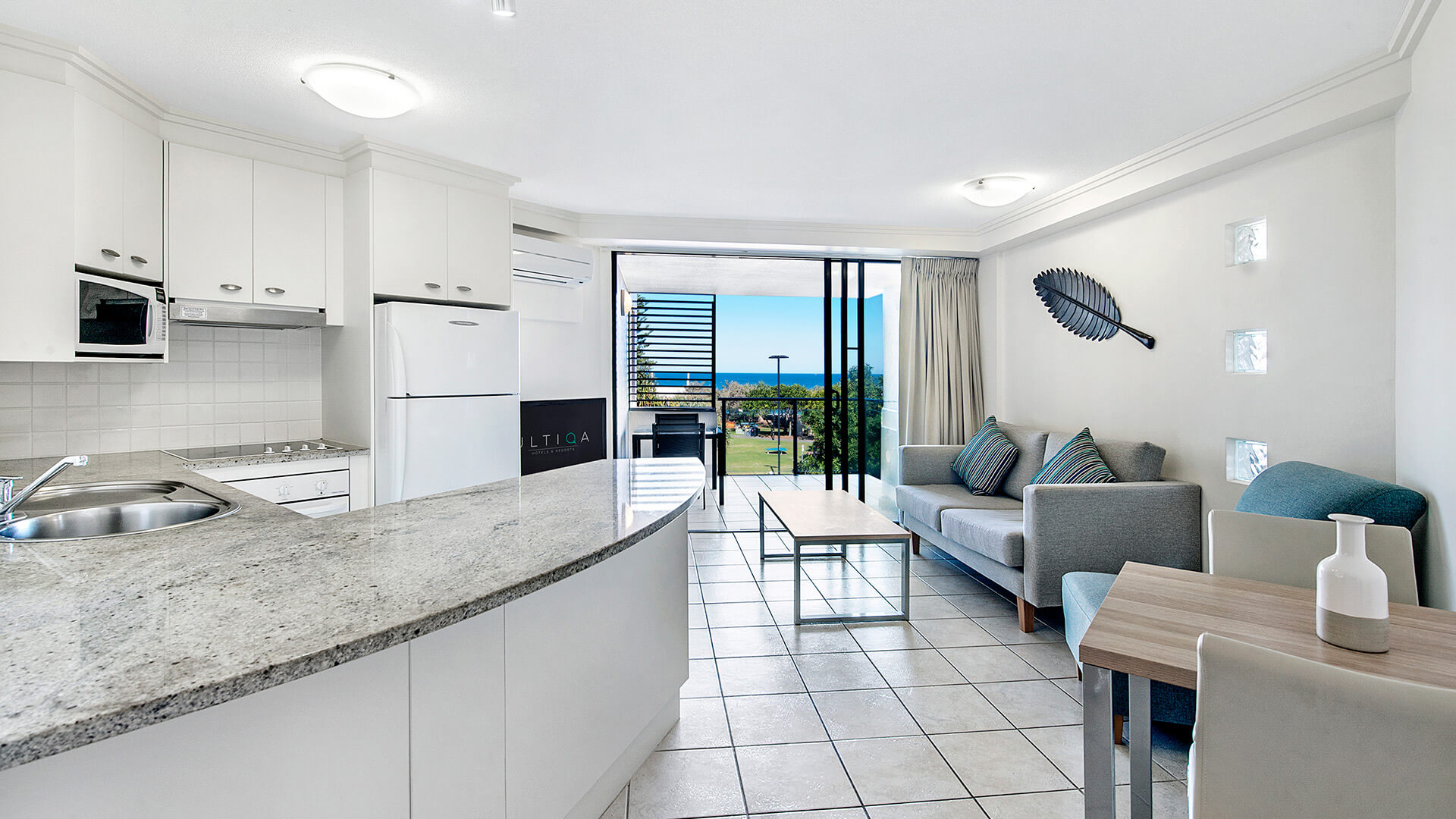 Kitchen and living area with balcony and ocean views in 1 Bedroom Apartment at ULTIQA Shearwater Resort.