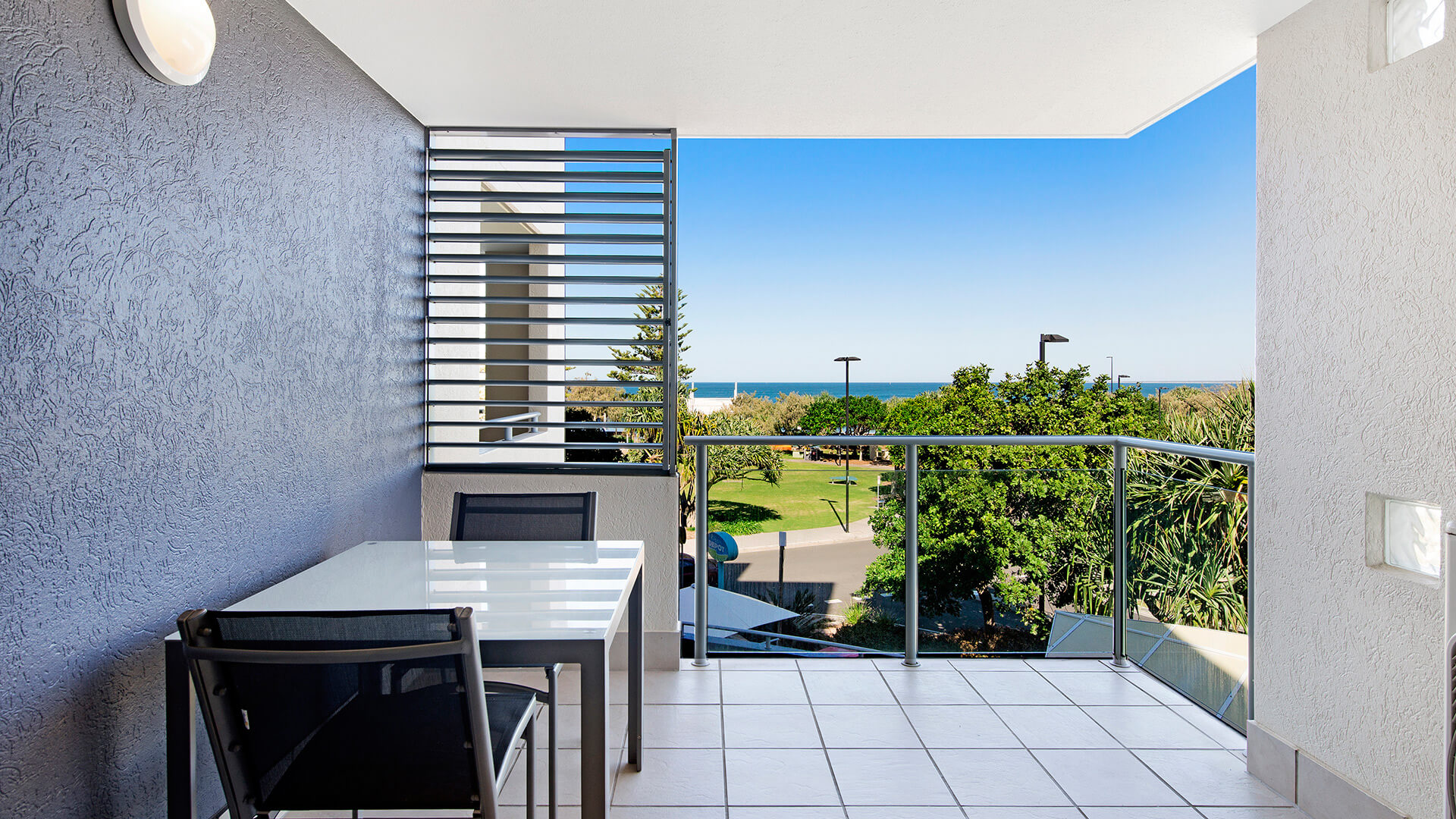 Private balcony with outdoor seating and ocean views from 1 Bedroom Apartment at ULTIQA Shearwater Resort.