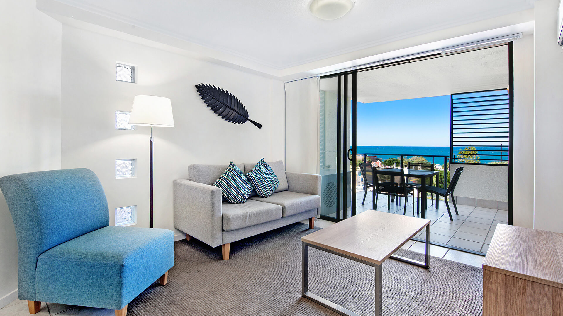 Living area with sofa and ocean views from balcony in 2 Bedroom Apartment at ULTIQA Shearwater Resort.