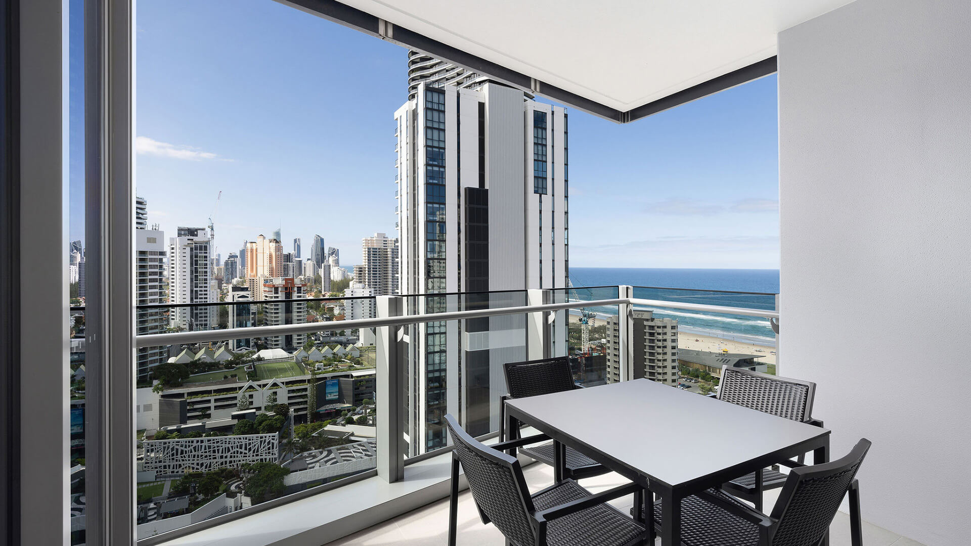 Private balcony with outdoor dining set and stunning ocean and city views in the 2 Bedroom Skyhome at ULTIQA Signature at Broadbeach.