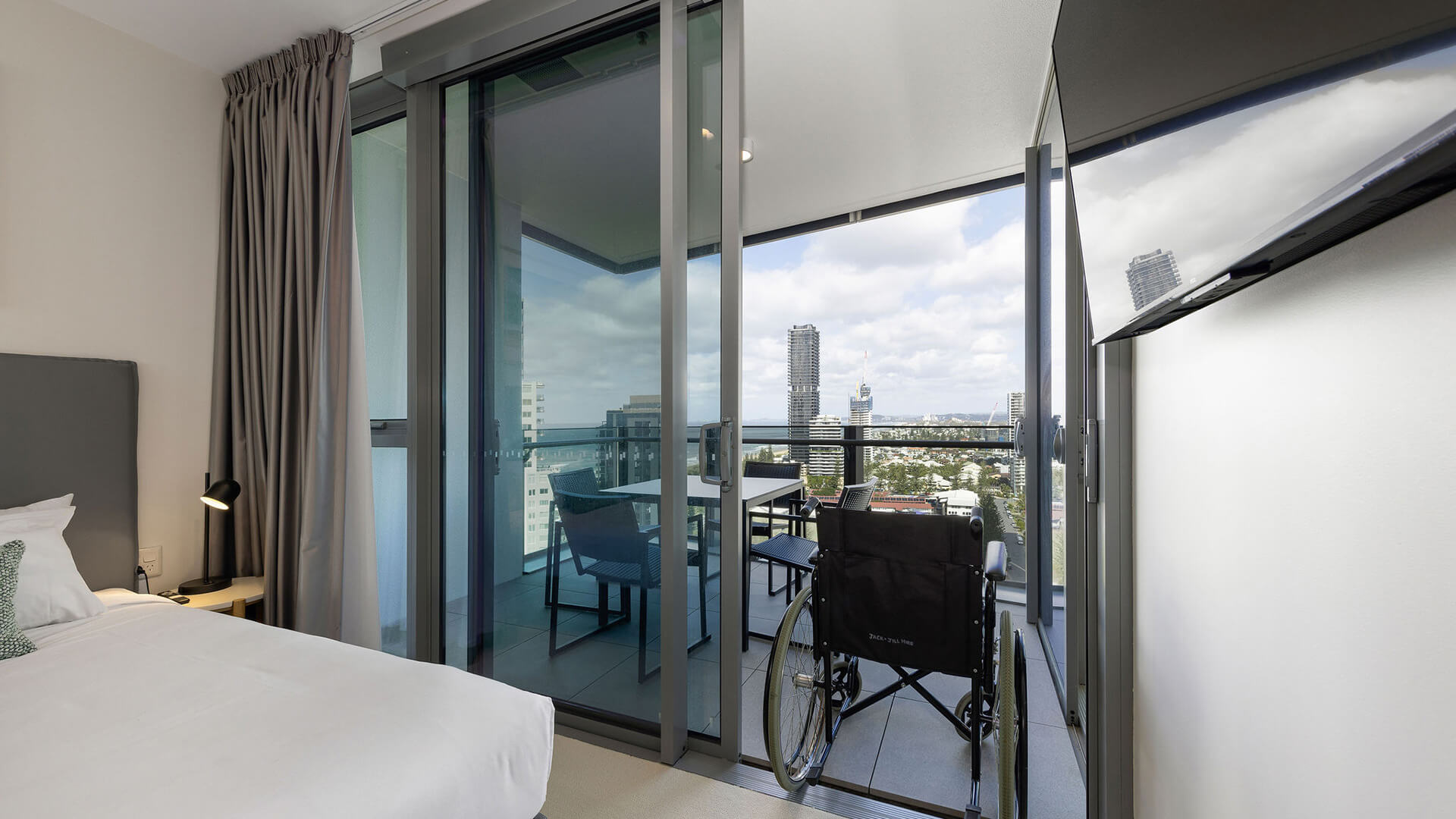 Wheelchair on balcony with city views in 2 Bedroom Accessible Suite at ULTIQA Signature at Broadbeach.