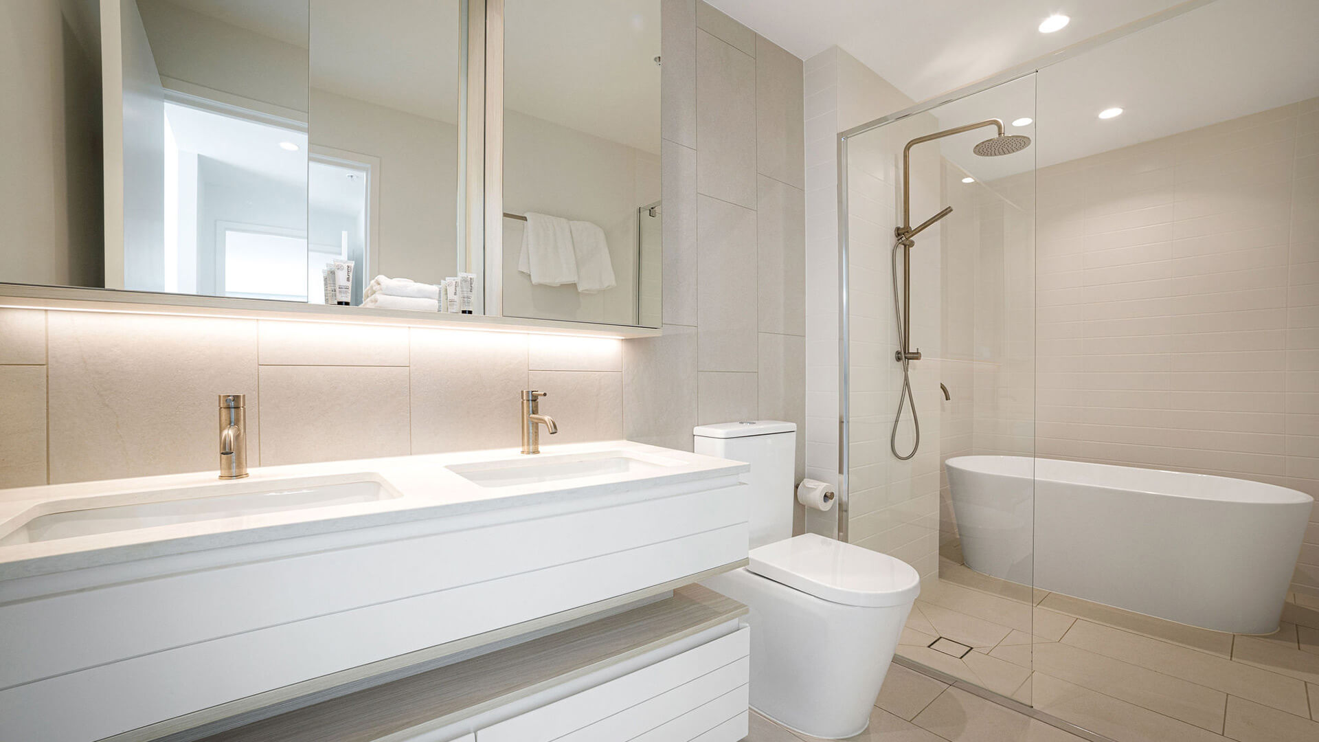 Modern bathroom in 3 Bedroom Suite at ULTIQA Signature, featuring double vanity, glass shower, freestanding tub, and sleek light-toned finishes.