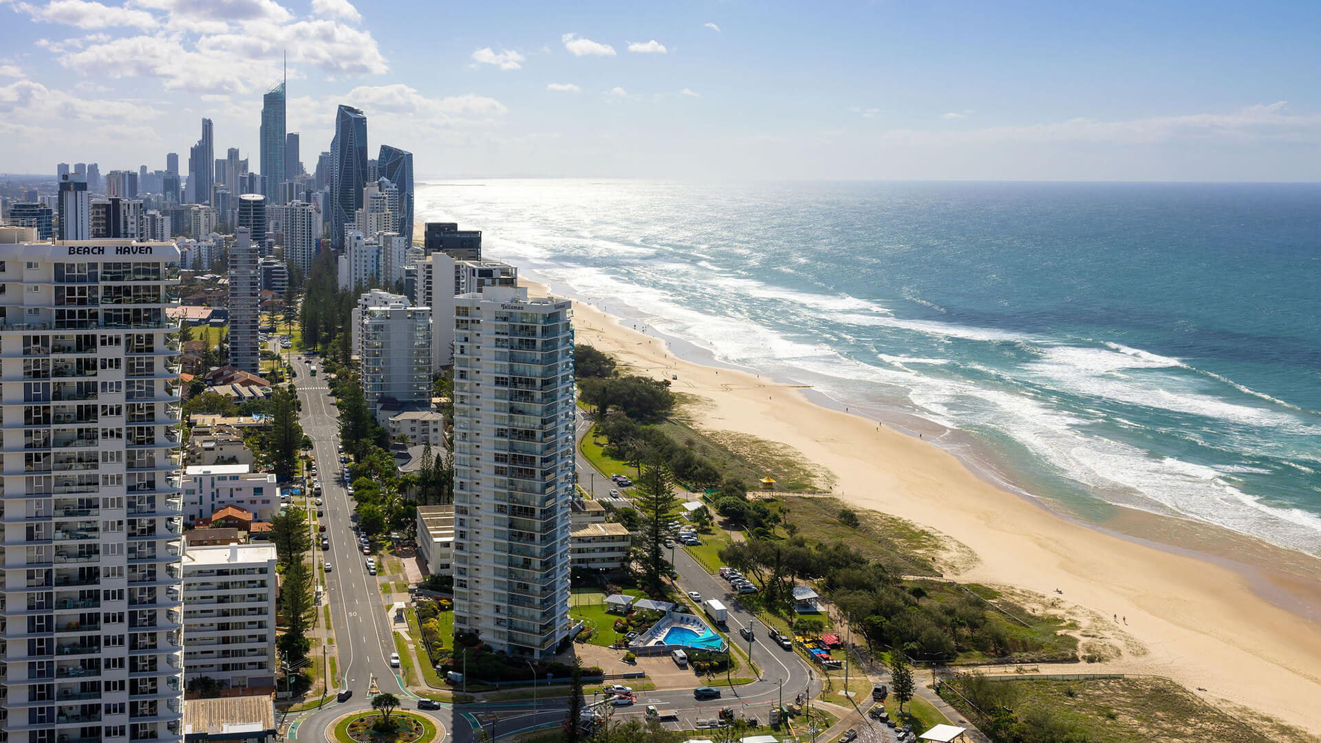 Aerial view of Gold Coast city skyline with high-rise buildings, beach, and ocean.