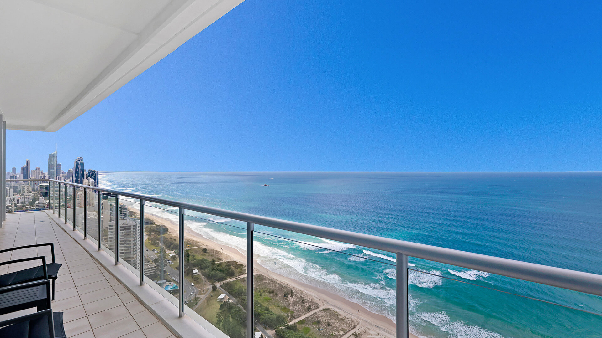 Balcony with seating and sweeping ocean and city skyline views from 4 Bedroom Ocean View Apartment at ULTIQA Air on Broadbeach.
