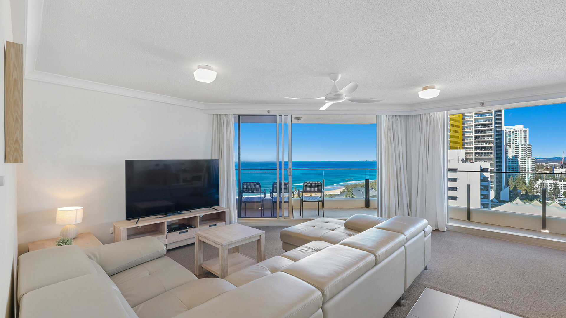 Living room in the 2 Bedroom Ocean View Apartment at ULTIQA Beach Haven with large sectional sofa, flat-screen TV, and ocean-facing balcony.