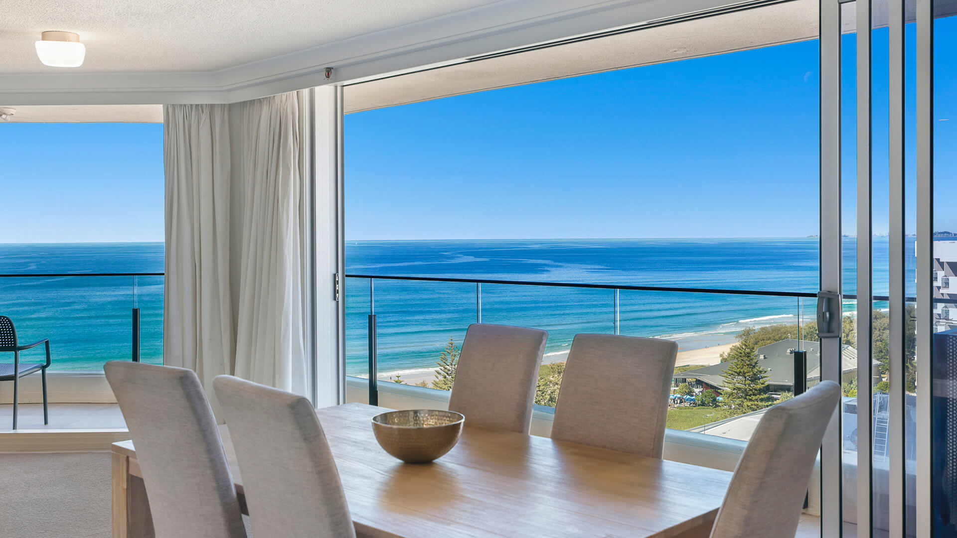 Dining table in the 2 Bedroom Ocean View Apartment at ULTIQA Beach Haven with stunning views of the beach and ocean horizon.