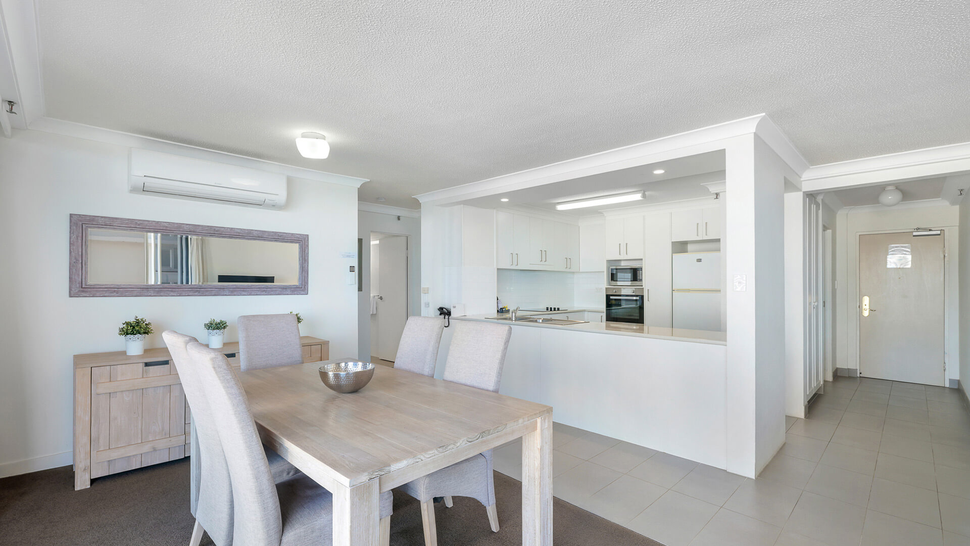Open-plan kitchen and dining area in the 2 Bedroom Ocean View Apartment at ULTIQA Beach Haven with modern appliances and coastal-style furnishings.