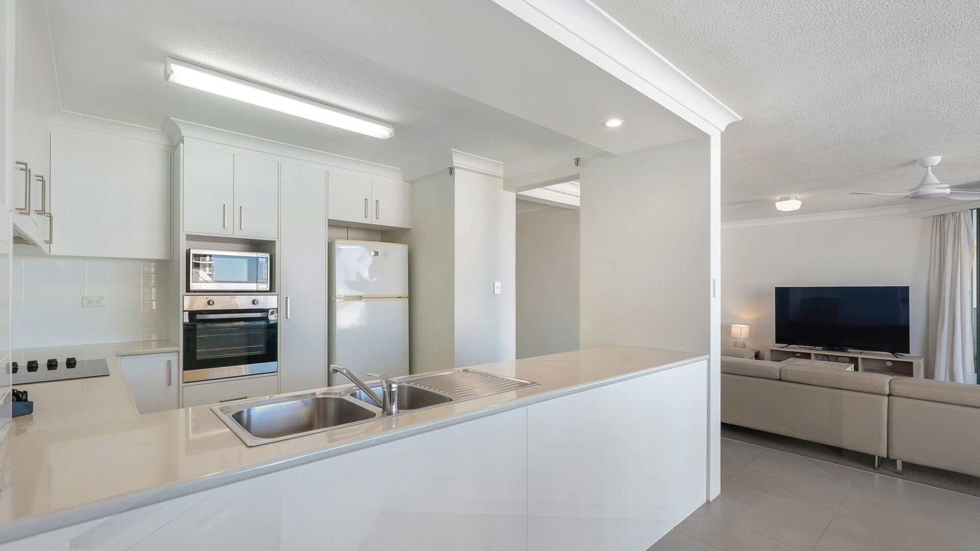 Kitchen in the 2 Bedroom Ocean View Apartment at ULTIQA Beach Haven with double sink, built-in oven, and open layout to living area.