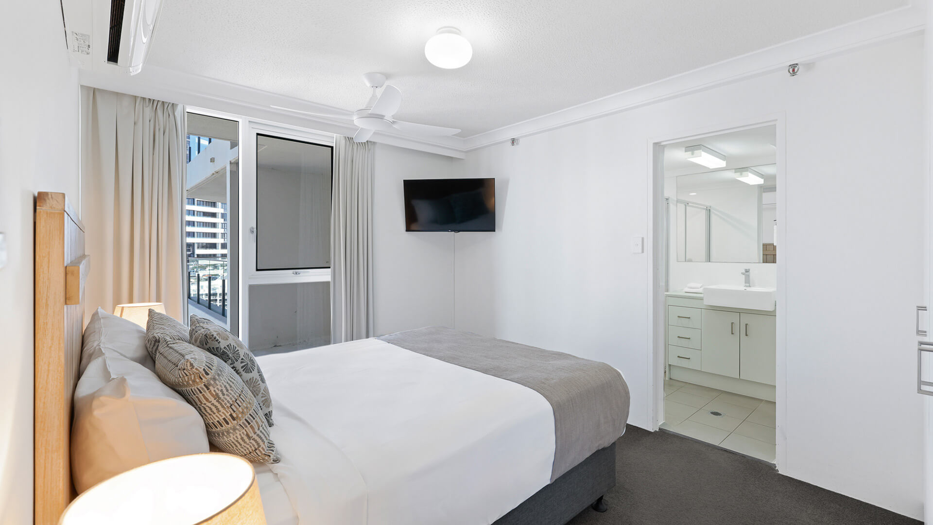 Master bedroom at ULTIQA Beach Haven featuring a king bed, flat-screen TV, air conditioning, and direct access to a private ensuite.
