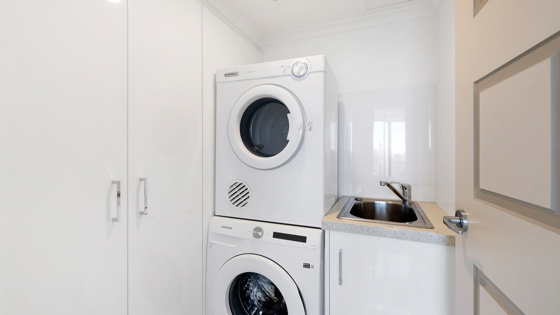 Fully equipped laundry in the Sub Penthouse at ULTIQA Beach Haven, featuring a washer, dryer, and sink.