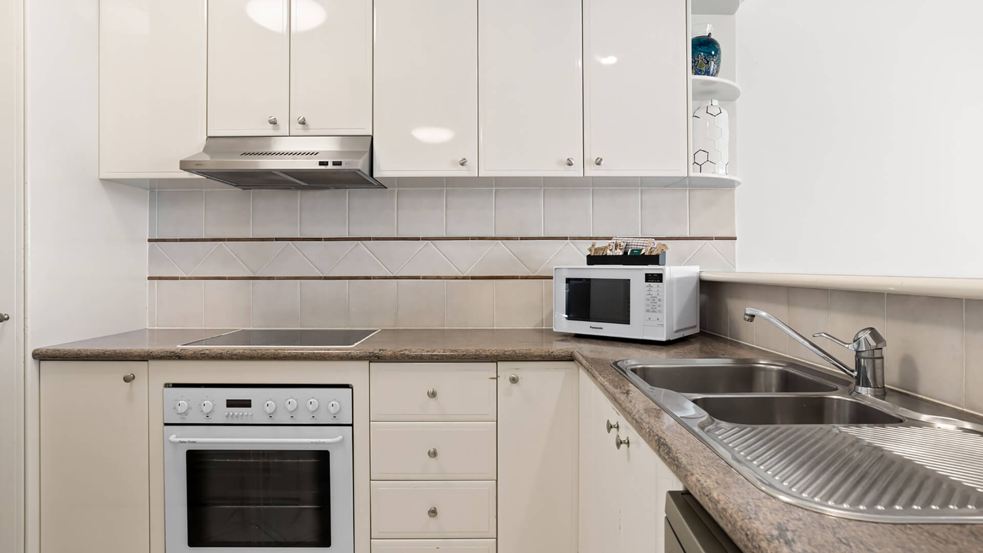 Full kitchen featuring an oven, cooktop, microwave, double sink, and ample bench space.