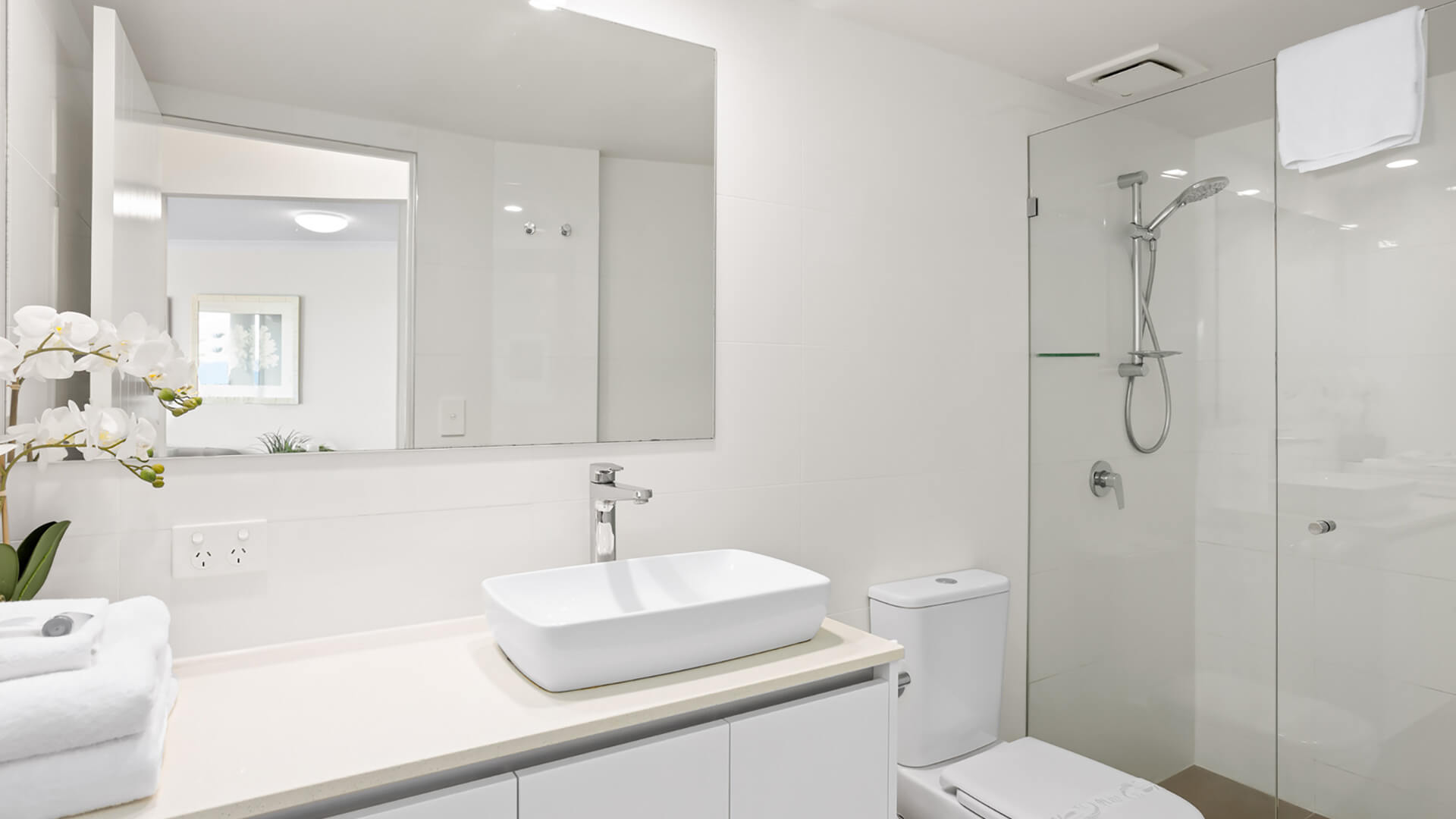 Modern bathroom featuring a walk-in shower, vanity, and fresh towels.