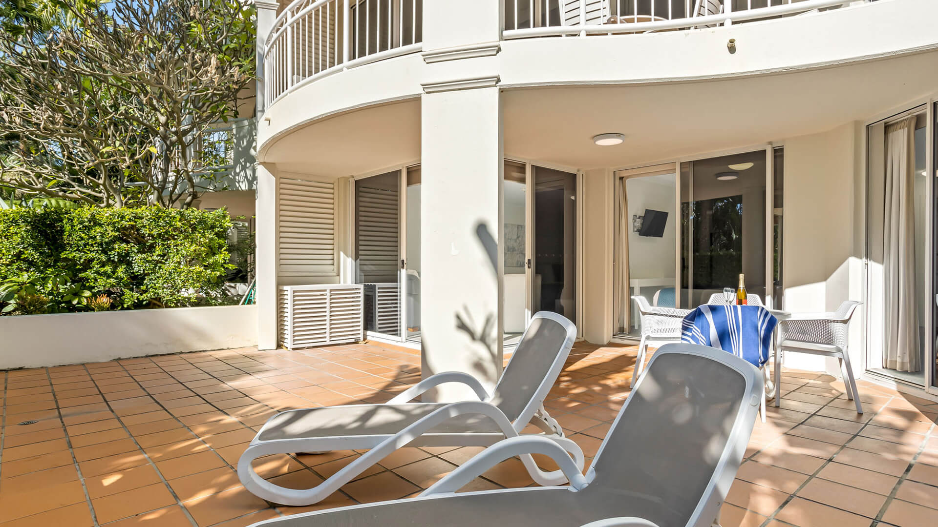 Spacious private terrace with sun loungers and outdoor dining in 2 Bedroom Garden View Apartment at ULTIQA Burleigh Mediterranean Resort.