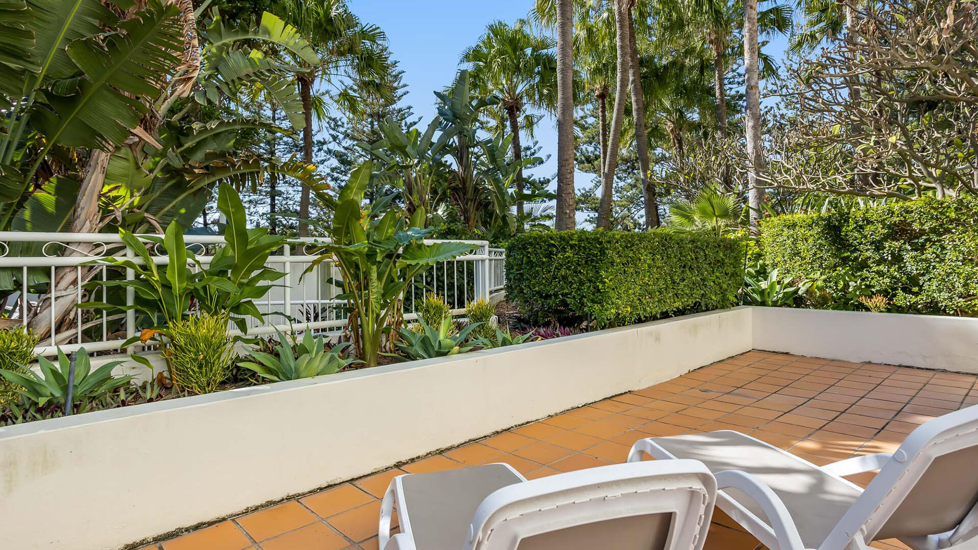 Garden-view terrace with sun loungers in 2 Bedroom Garden View Apartment at ULTIQA Burleigh Mediterranean Resort.