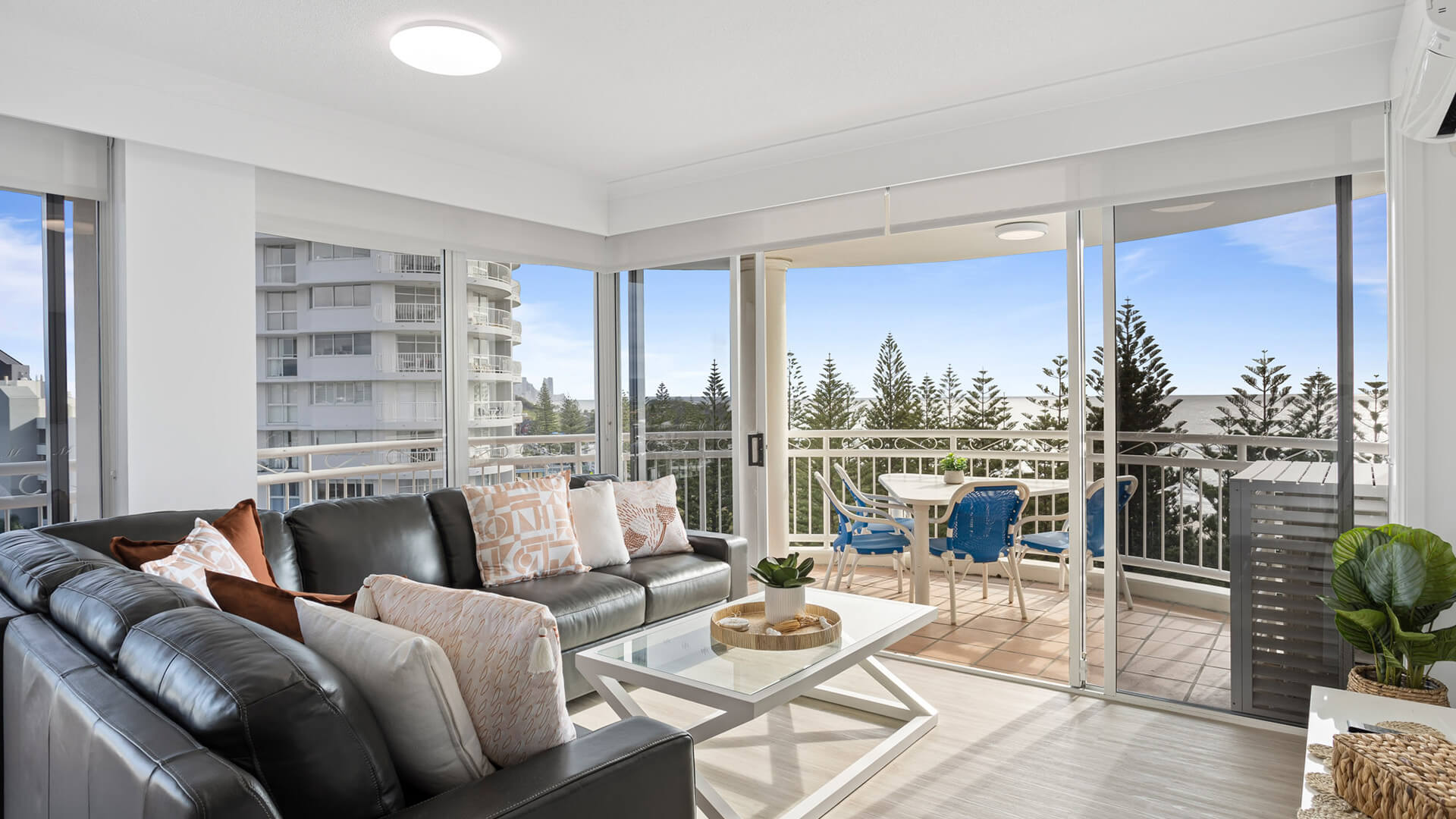 Living area with leather lounge and ocean-view balcony in 3 Bedroom Superior Ocean View Apartment at ULTIQA Burleigh Mediterranean Resort.