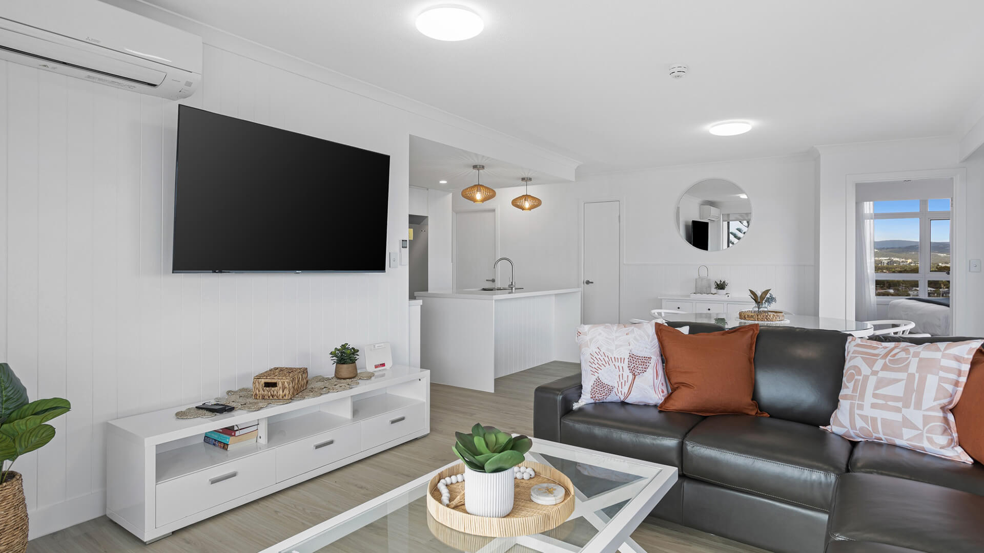 Open-plan living area with leather lounge, smart TV, and dining space in 3 Bedroom Superior Ocean View Apartment at ULTIQA Burleigh Mediterranean Resort.