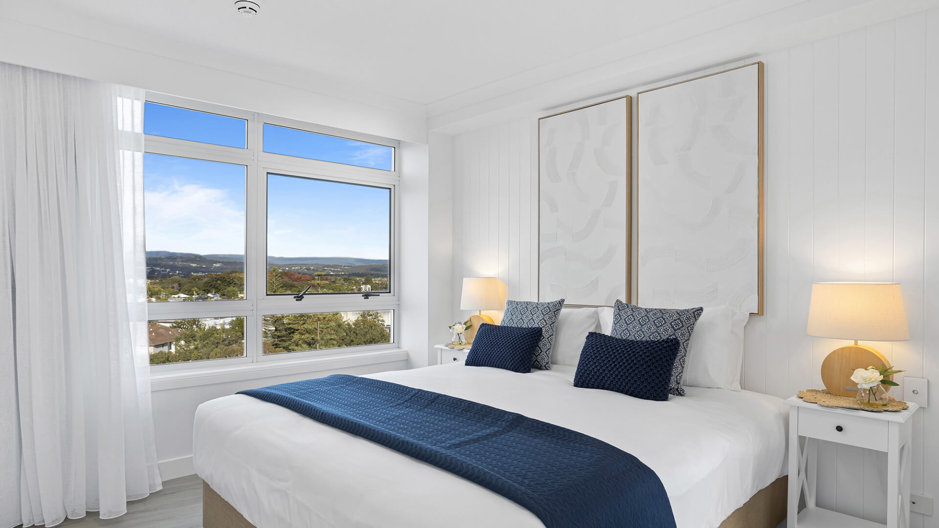Bright bedroom with king bed, navy accents, and scenic hinterland views in 3 Bedroom Superior Ocean View Apartment at ULTIQA Burleigh Mediterranean Resort.