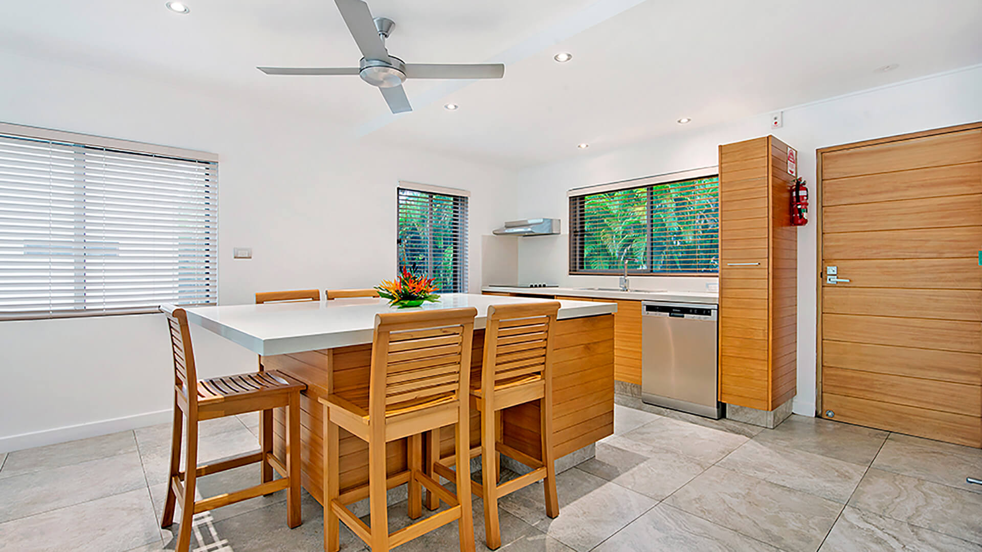 Modern kitchen and dining area in 2 Bedroom Deluxe Apartment at ULTIQA Fiji with island seating and tropical garden views.