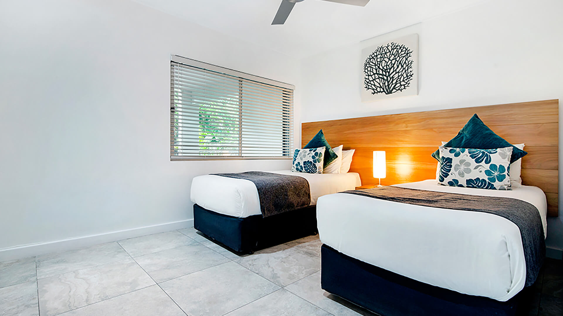 Second bedroom in 2 Bedroom Deluxe Apartment at ULTIQA Fiji with two single beds, modern decor, and tropical garden views.