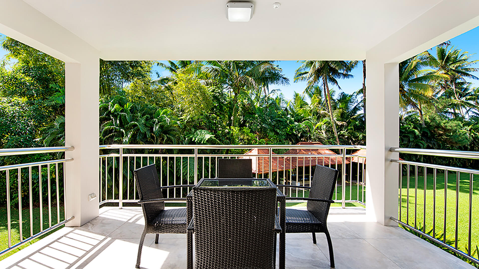 Private balcony in 2 Bedroom Deluxe Apartment at ULTIQA Fiji with outdoor dining set and lush tropical garden views.