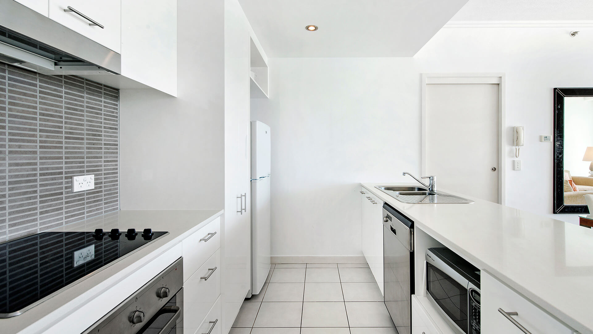 Modern kitchen with oven, cooktop, microwave, and full-size fridge in the 1 Bedroom Apartment at ULTIQA Freshwater Point Resort.