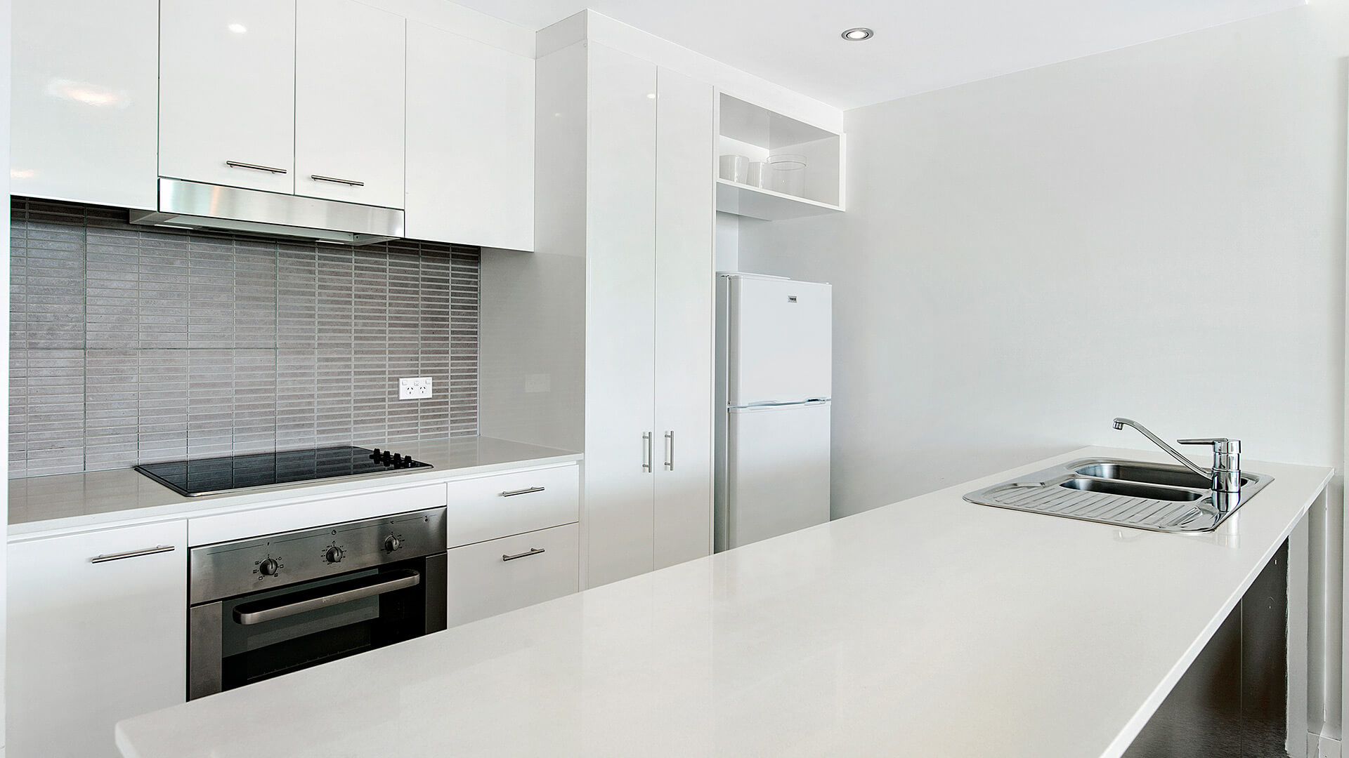 Fully equipped kitchen with sleek benchtops, cooktop, oven, and full-size fridge in the 1 Bedroom Apartment at ULTIQA Freshwater Point Resort.