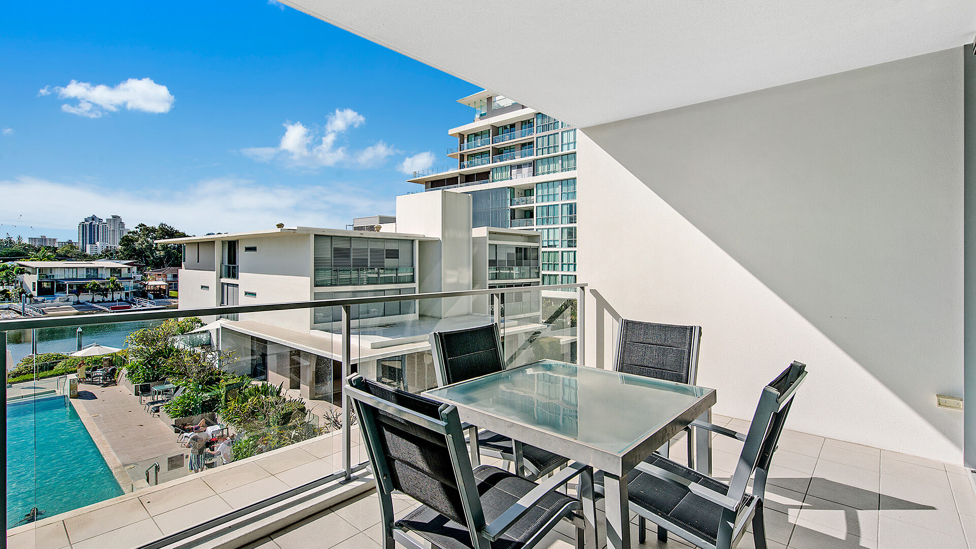 Balcony at ULTIQA Freshwater Point Resort 1 Bedroom Apartment featuring outdoor dining and views of the canal and resort pool.